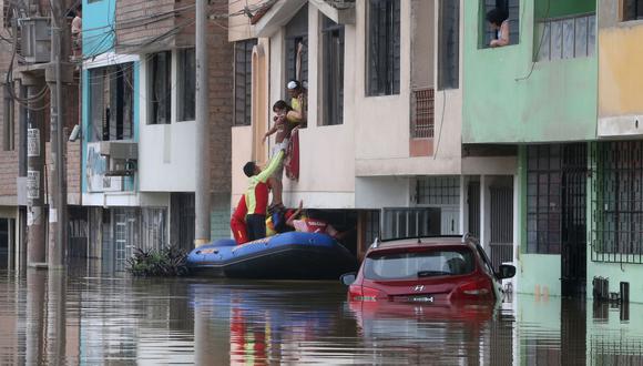 Miembros de la Policía Nacional ayudan a una mujer a salir de su vivienda. El aniego inundó casi el primer piso de las viviendas de San Juan de Lurigancho. (Foto: Andina).