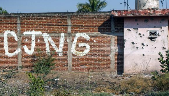 Vista de un muro acribillado a balazos con las iniciales del grupo criminal Cartel Jalisco Nueva Generación (CJNG) en la entrada de la comunidad de Aguililla, estado de Michoacán, México, el 23 de abril de 2021. (Foto de ENRIQUE CASTRO / AFP)