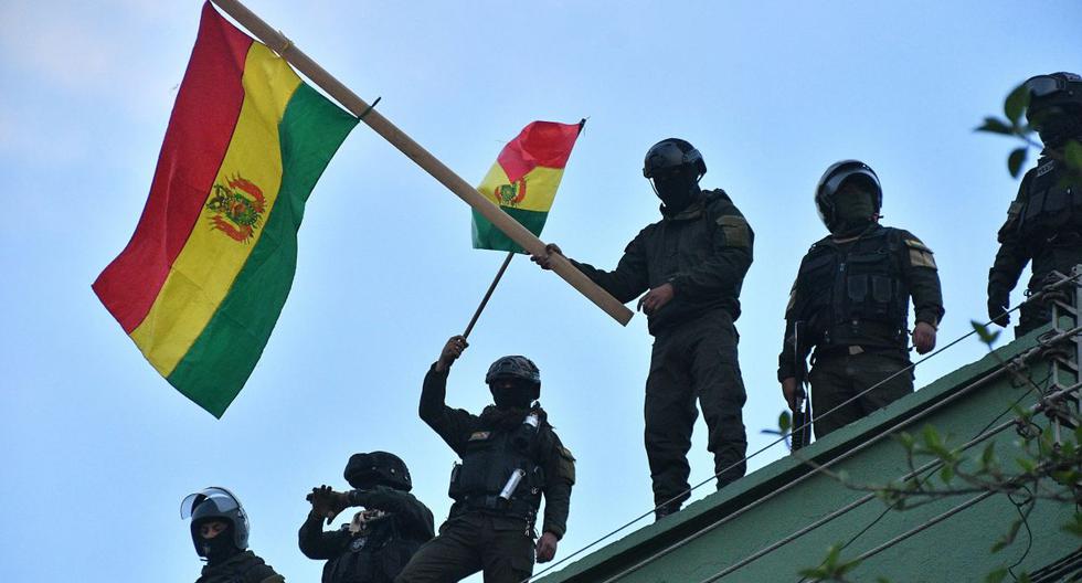 Policías bolivianos ondean banderas del país en el techo de una unidad policial este viernes en Cochabamba (Bolivia). (Foto: EFE)