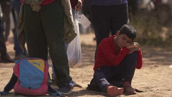 Un niño sentado en el suelo mientras los migrantes esperan ser procesados por la Patrulla Fronteriza de EE. UU. después de cruzar ilegalmente la frontera sur de EE. UU. con México el 9 de octubre de 2022 en Eagle Pass, Texas. (Foto de allison cena / AFP)