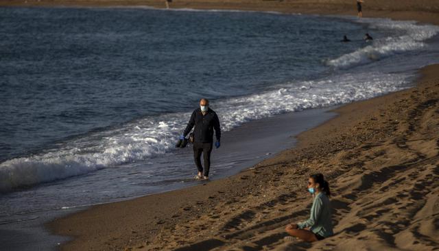 La gente se sienta y camina en una playa reabierta de Barcelona para actividades deportivas después de las medidas de cierre por el coronavirus. (AP/Emilio Morenatti).