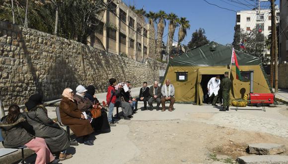 Los sirios esperan afuera de una carpa en un hospital de campaña bielorruso instalado en la ciudad norteña de Alepo, controlada por el gobierno, el 20 de febrero de 2023, luego del terremoto que azotó Turquía y Siria a principios de este mes. (Foto por AFP)