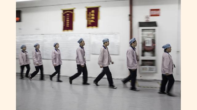 Luego de pasar a través de detectores de metales para localizar dispositivos equipados con cámaras que podrían usarse para filtrar imágenes de productos nuevos aún no salidos al mercado, los trabajadores siguen flechas dibujadas en el piso y carteles insp