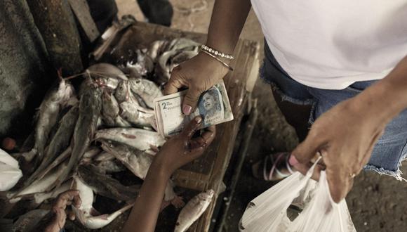 Un cliente paga pescado en un mercado de alimentos en Riohacha, Colombia, el sábado 13 de agosto de 2022. Los precios altísimos de los alimentos y el combustible en América Latina están afectando más a los pobres, creando un polvorín político que es una advertencia para el mundo.