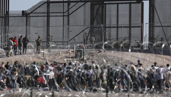 Migrantes esperan a orillas del Río Grande para ser procesados por la Patrulla Fronteriza Sector El Paso, Texas, después de cruzar desde Ciudad Juárez, México el 10 de mayo de 2023. (Foto por HERIKA MARTÍNEZ / AFP)
