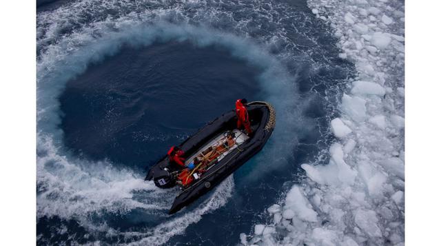 Oficiales de la marina chilena giran su zodiac en círculos para limpiar el mar de hielo y acercarse al buque Aquiles de la Armada de su país, en el que recogerán científicos internacionales que trabajarán en la estación científica Bernardo O'Higgins 