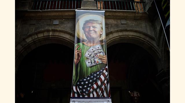 La muestra también exhibe enormes banners o gigantografías en su patio central. En la foto se observa una parodia del Sagrado Corazón de Jesús, solo que con Donald Trump, y billetes en lugar de corazón.