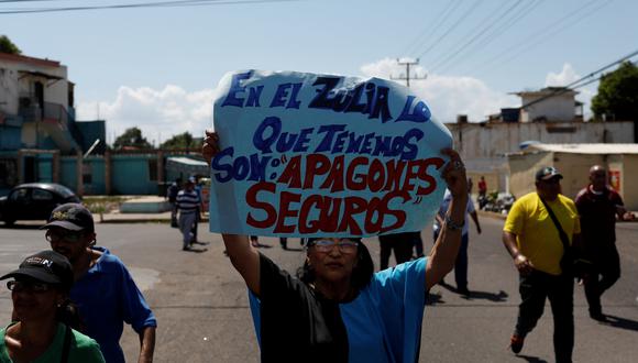 Una mujer sostiene una pancarta que dice "En Zulia lo que tenemos son apagones por sentado" frente a una instalación de la compañía eléctrica nacional Corpoelec durante una protesta contra apagones crónicos y escasez de agua en Maracaibo. (Foto: Reut