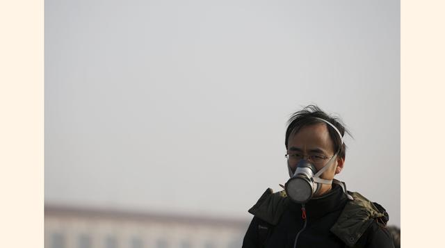 Un ciudadano chino camina por la Plaza Tiananmen protegido con una máscara para evitar la alta contaminación en Beijing.