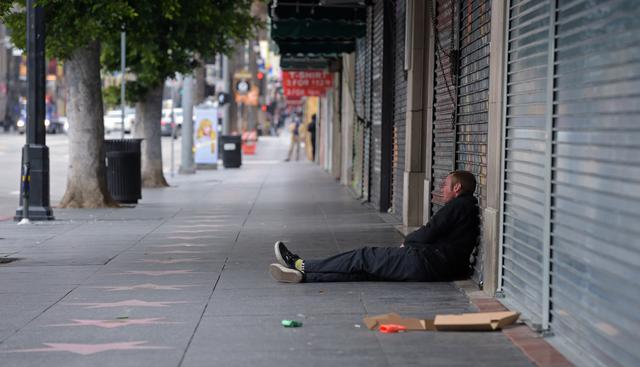 Un hombre se sienta frente a las tiendas cerradas del Hollywood Boulevard en Los Ángeles, California. (AFP).