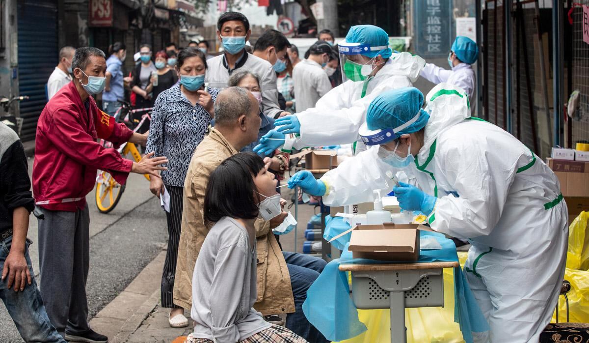 Los trabajadores médicos toman muestras de hisopos de los residentes para analizar el coronavirus COVID-19, en una calle de Wuhan. (Foto: AFP/STR)