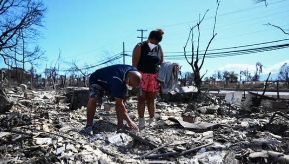 Davilynn Severson y Hano Ganer buscan pertenencias entre las cenizas de la casa de su familia después de un incendio forestal en Lahaina, en el oeste de Maui, Hawái. (Foto: AFP)