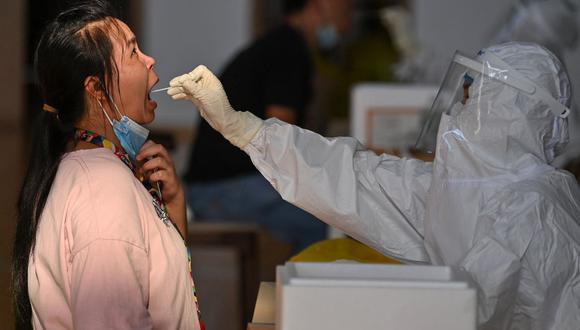 Esta foto tomada el 5 de agosto de 2021 muestra a una persona siendo sometida a una prueba de coronavirus Covid-19 en el gimnasio de una empresa en Wuhan, China. (Foto de STR / AFP).
