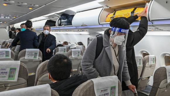 Un pasajero con un protector facial y una máscara en medio de la pandemia de covid-19 aborda un vuelo nacional en el Aeropuerto Internacional de Shanghái Pudong en Shanghái el 3 de enero de 2023. (Foto de HECTOR RETAMAL / AFP)