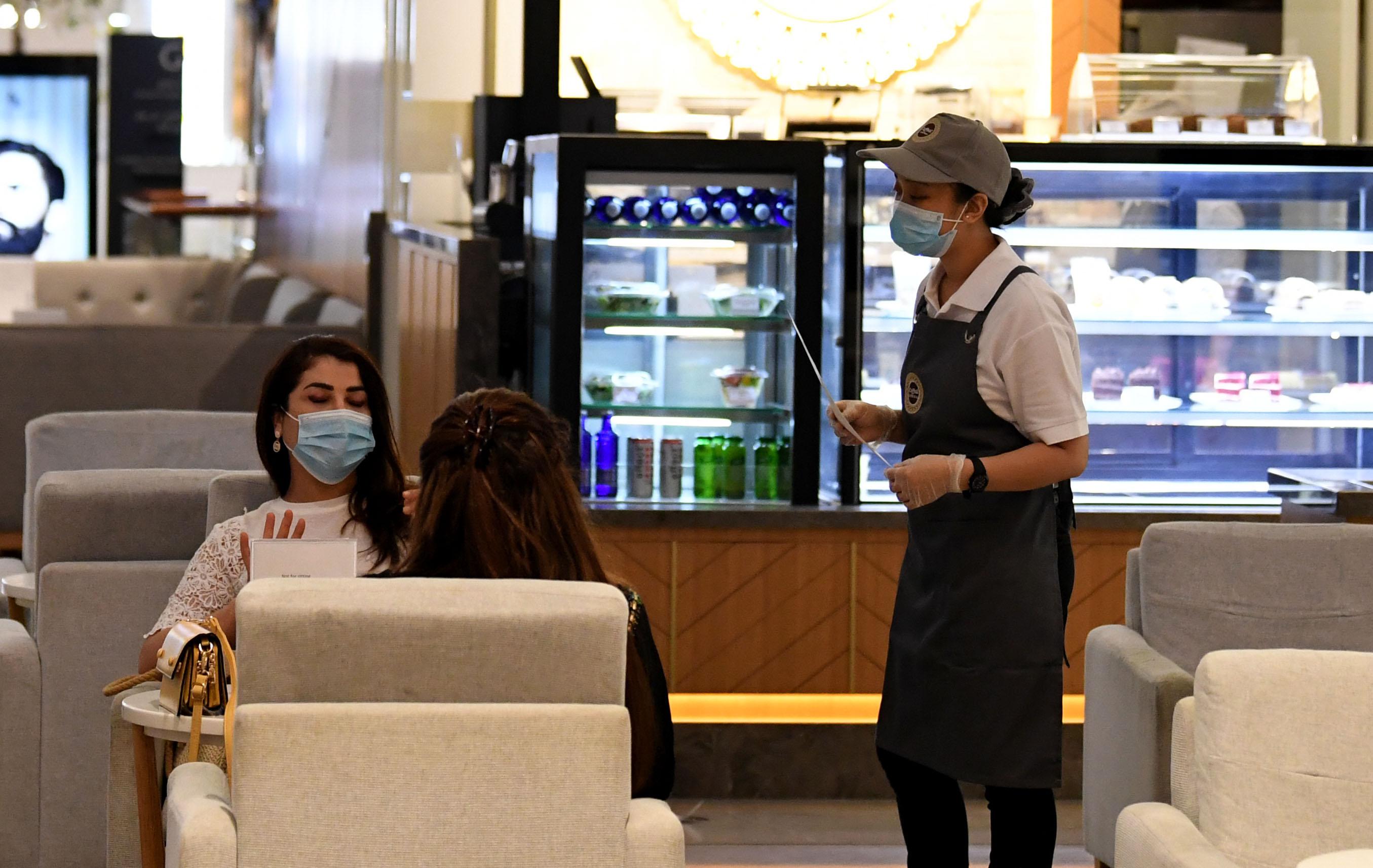 Las mujeres, que usan máscaras para protegerse contra el coronavirus, se sientan en un restaurante en el Dubai Mall. (Karim SAHIB / AFP).