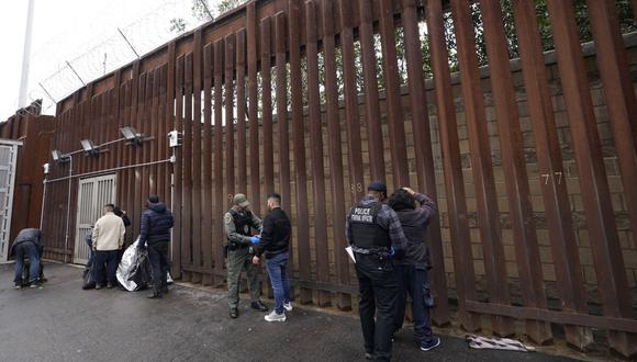 Oficiales federales estadounidenses le quitan las esposas a hombres antes de liberarlos cerca de la muralla fronteriza en San Diego (Foto: AP)