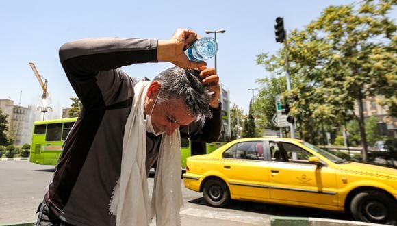 Un hombre se vierte agua en la cabeza de una botella para refrescarse durante una ola de calor en Teherán el 11 de julio de 2023. (Foto de ATTA KENARE / AFP)