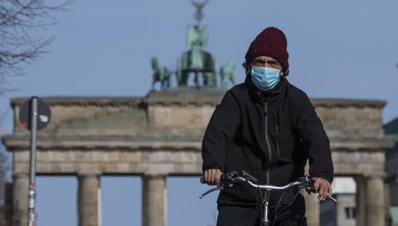 Un hombre con una máscara facial se desplaza frente a la Puerta de Brandenburgo en Berlín, en medio de la pandemia de coronavirus Covid-19. (Foto: AFP/John MACDOUGALL)