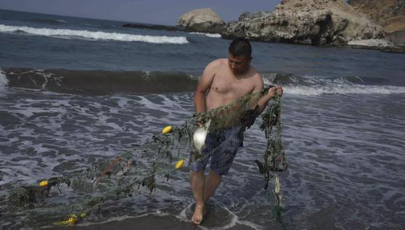 El pescador Ronal Astolingon recupera un pez y basura de su net en Ventanilla, Perú. Dos días después de lo que las autoridades consideran el peor derrame de petróleo en la historia de Perú, las playas siguen cerradas para los turistas y y el sustento de los pescadores está destruido. (AP Foto/Guadalupe Pardo) (Guadalupe Pardo / Associated Press)