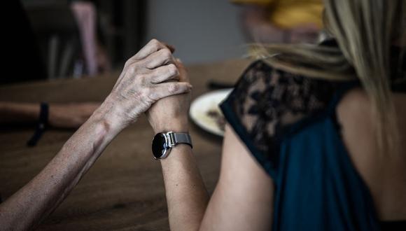 Un voluntario sosteniendo la mano de un paciente con Alzheimer durante el almuerzo en el restaurante del sitio Landais Alzheimer para pacientes con Alzheimer en Dax, suroeste de Francia. (Foto de Philippe LÓPEZ / AFP)