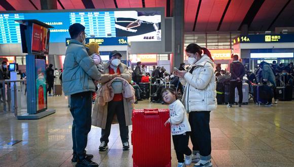 Una familia espera para registrarse en una estación de tren en Beijing el 12 de enero de 2023, cuando comienza la migración anual con personas que regresan a sus lugares de origen para las celebraciones del Año Nuevo Lunar. (Foto de WANG ZHAO/AFP)
