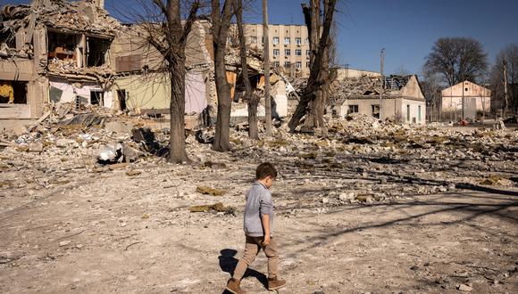 Un niño camina frente a una escuela dañada en la ciudad de Zhytomyr, en el norte de Ucrania, el 23 de marzo de 2022. (Foto de FADEL SENNA / AFP)