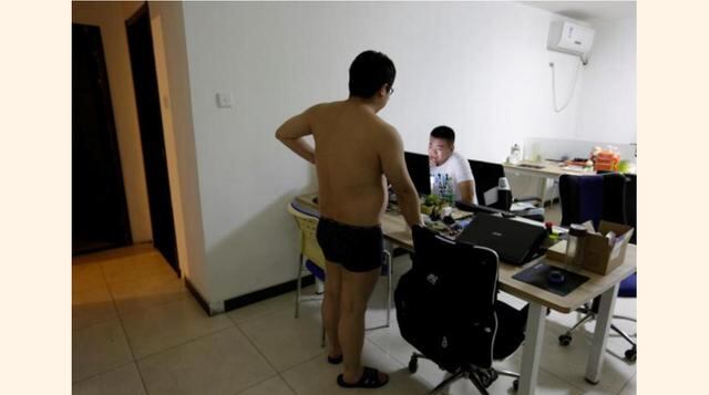 Zhang Huichao, un programador de N-Wei (Beijing) Technology Company Limited, conversa con su colega Yan Xiaolong antes de irse a dormir, en el sala de un departamento que renta su empresa como oficina y residencia de empleados en Pekín, China. (Foto: Reut