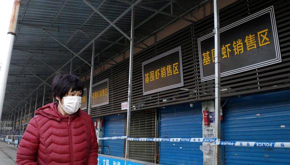 Una mujer camina frente al mercado mayorista de mariscos cerrado de Huanan, donde las autoridades sanitarias dicen que un hombre que murió de una enfermedad respiratoria había comprado productos, en la ciudad de Wuhan, provincia de Hubei, el 12 de enero de 2020. (Foto de Noel Celis / AFP)