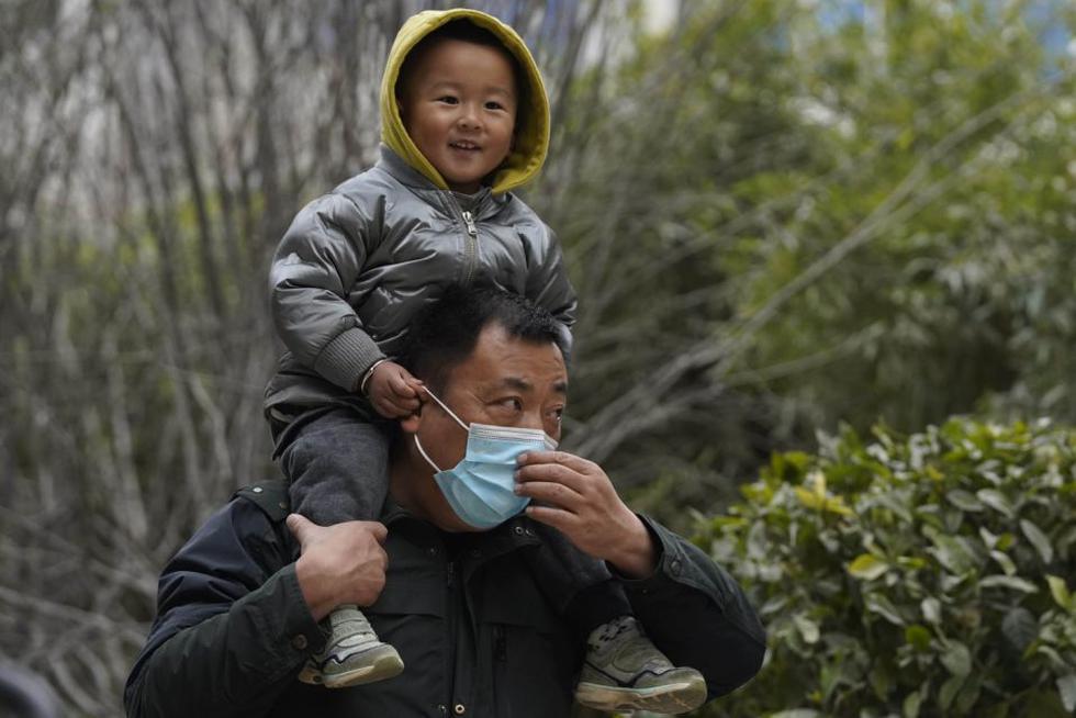 Un niño sonríe sobre los hombros de un hombre que lleva mascarilla, mientras que pasean por las calles de Wuhan. La normalidad es absoluta, muy diferente a los primeros meses de 2020. (AP Photo/Ng Han Guan)