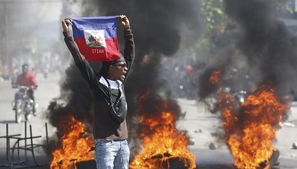 Un manifestante muestra una bandera haitiana durante una protesta para exigir la renuncia del primer ministro del país, Ariel Henry, en Puerto Príncipe.  (AP Foto/Odelyn Joseph).