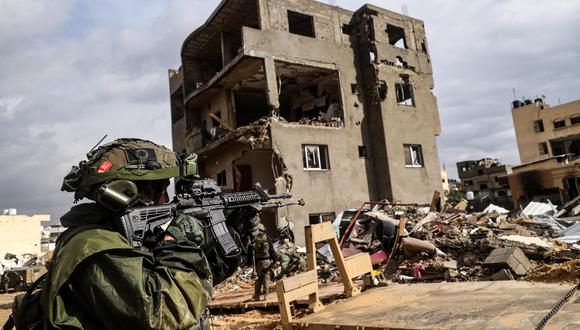 Esta fotografía tomada durante un recorrido mediático organizado por el ejército israelí el 27 de enero de 2024 muestra a un soldado israelí apuntando con su arma frente a un edificio destruido. (Foto de Nicolás GARCÍA / AFP)