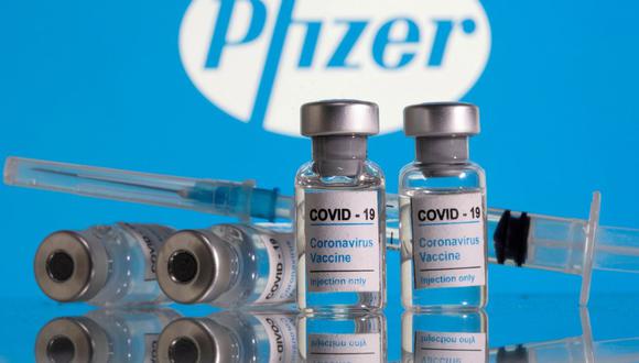 En esta ilustración tomada el 9 de febrero de 2021, se ven viales etiquetados como "Vacuna contra el coronavirus COVID-19" y una jeringa frente al logotipo de Pfizer. (REUTERS/Dado Ruvic).