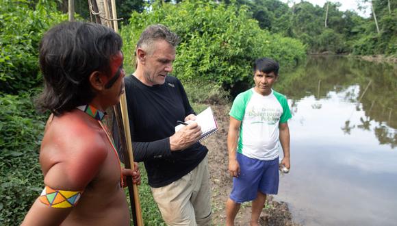 El veterano corresponsal extranjero Dom Phillips (centro) habla con dos hombres indígenas en Aldeia Maloca Papi,  estado de Roraima, Brasil, en noviembre de 2019. Phillips y el indigenista brasilero Bruno Pereira fueron asesinados en junio de este año tras una expedición en el Valle del Javarí. (Foto de Joao LAET / AFP)