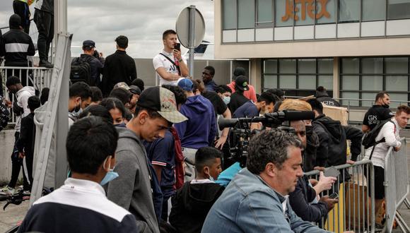 Periodistas y simpatizantes se reúnen frente al aeropuerto de Le Bourget, al norte de París, cuando se espera la llegada del futbolista argentino Lionel Messi, el 9 de agosto de 2021. (GEOFFROY VAN DER HASSELT / AFP).