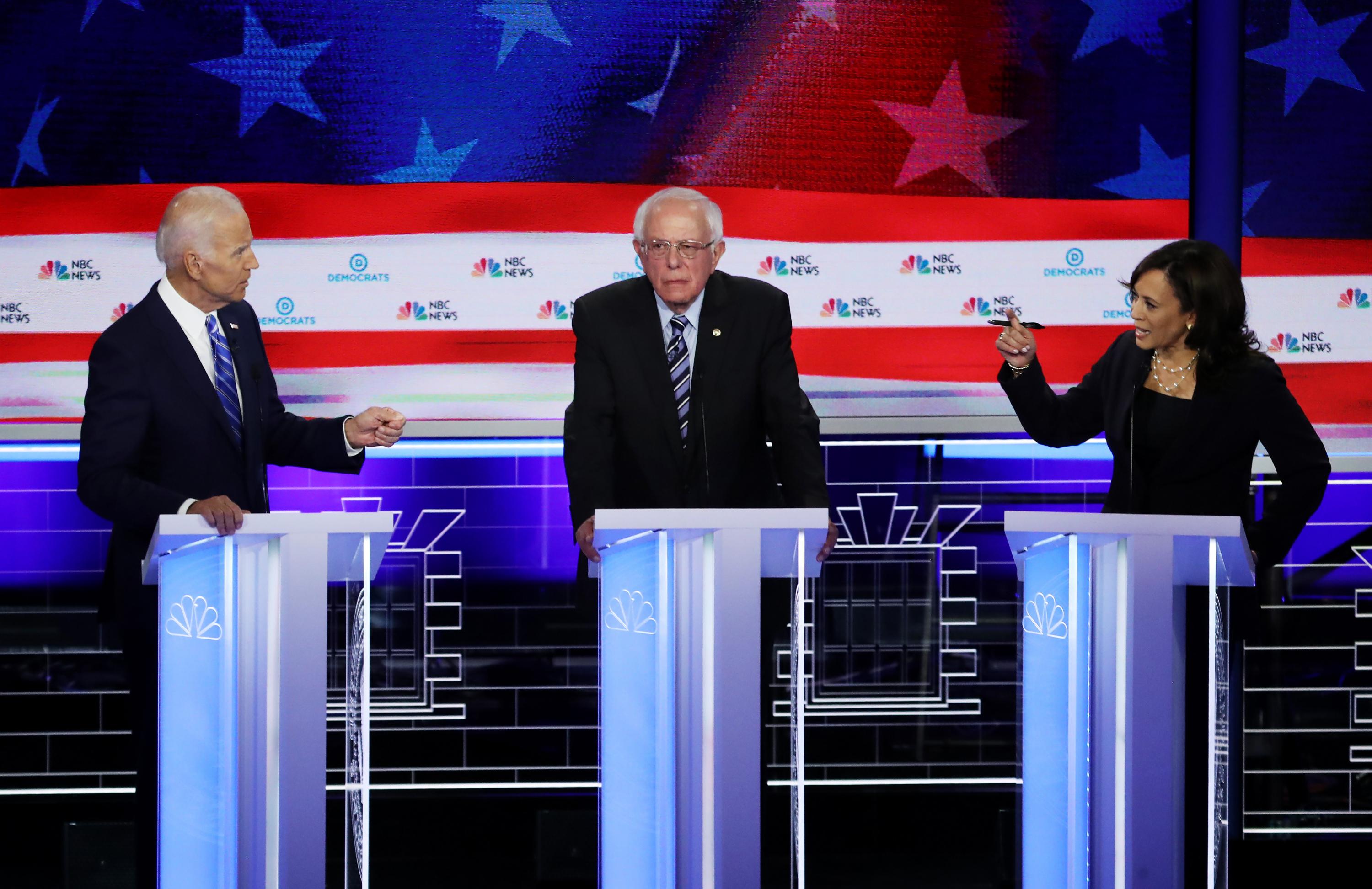 la senadora Kamala Harris (R) (D-CA) y el ex vicepresidente Joe Biden (L) hablan mientras el senador Bernie Sanders (I-VT) observa durante la segunda noche de la primera presidencia demócrata. Foto: AFP