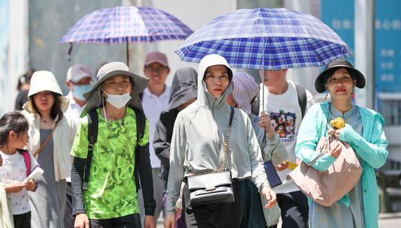 La gente se protege del sol cuando la temperatura alcanza los 40.1 grados centígrados en Beijing el 6 de julio. Fotógrafo: Jia Tianyong/China News Service/VCG/Getty Images