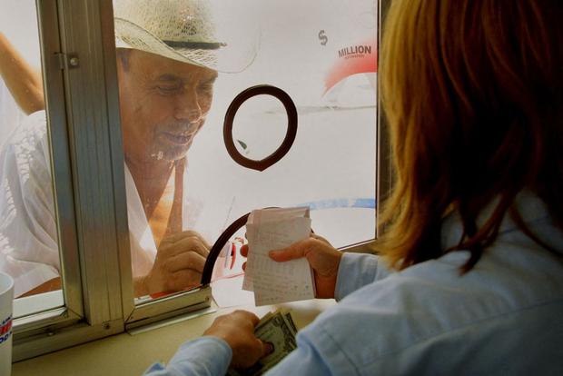 Un vendedor le entrega sus boletos de Powerball a un cliente desde un stand especial configurado para manejar las largas colas para comprar boletos en una gasolinera en Hammond, Indiana (Foto: Scott Olson / AFP)