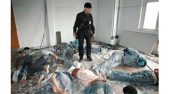 Porto Alegre, Brasil. Homicidios: 1.442. Población: 4.161.237. Tasa de homicidios: 34.65. En la imagen: Un oficial de la policía federal camina junto a los sospechosos arrestados por pertenecer a una banda de crimen organizado en Porto Alegre. (Foto: AP)