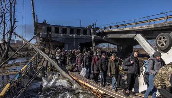 Residentes con su equipaje cruzan un puente destruido mientras huyen de la ciudad de primera línea de Irpin, región de Kiev (Kiev), Ucrania. (EFE/EPA/ROMAN PILIPEY).