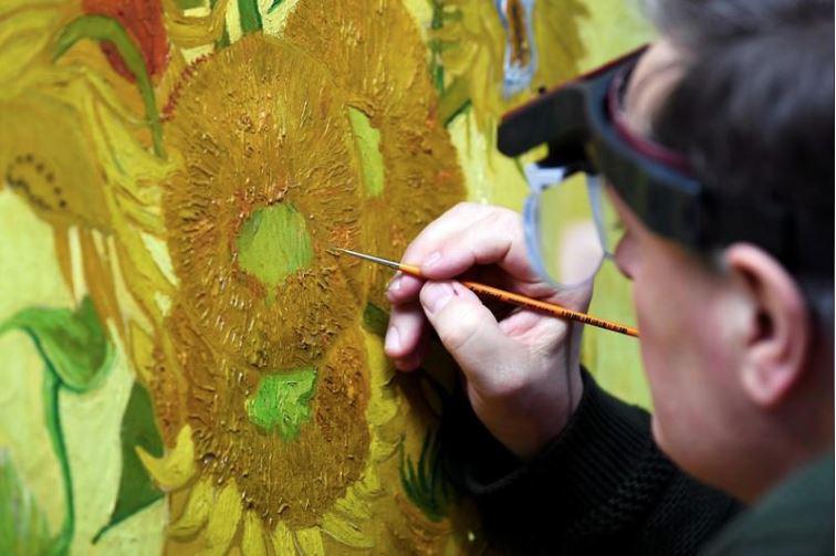 El especialista Rene Boitelle restaura el cuadro "Girasoles" de Vincent van Gogh en el Van Gogh Museum de Amsterdam, Holanda, el 24 de enero de 2019. (Foto: Reuters).