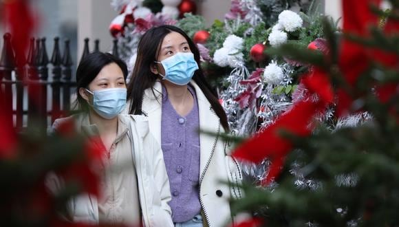 Los compradores que usan cubiertas para la cara para combatir la propagación del coronavirus caminan por las decoraciones navideñas en Covent Garden, en el centro de Londres, el 9 de diciembre de 2021. (Foto: Hollie Adams / AFP)