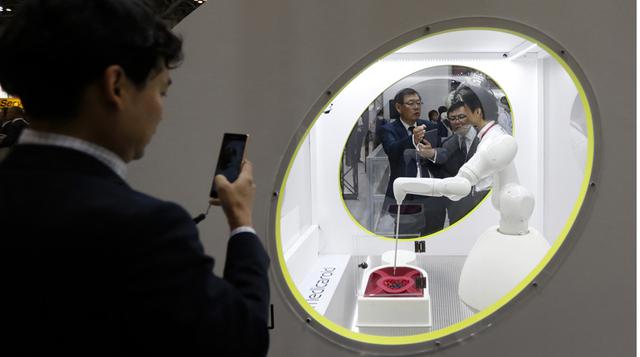 Un asistente toma una fotografía de un robot médico Medicaroid Corp. en la Exposición Internacional Robot 2015 en Tokio.
