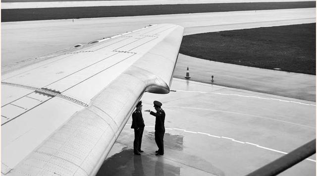 Confidencias, dos miembros de Air Koryo charlan de manera distendida bajo las alas de uno de los aviones de la línea.