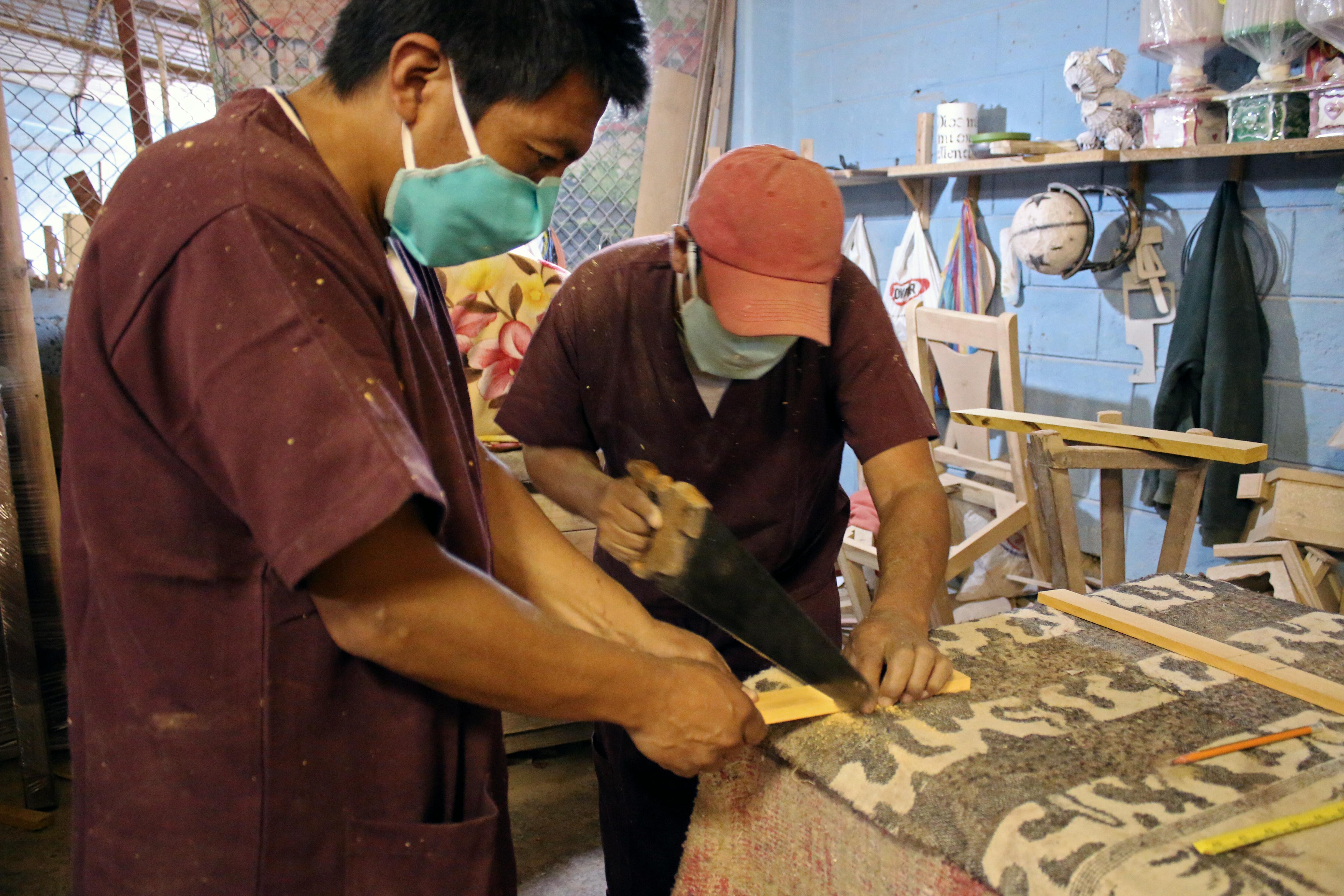 Handout photo released by the Ecuadorean Ministry of Environment of prisoners wearing face masks as they work on the making of coffins in Ambato, Ecuador on April 8, 2020. - The Ministry of Environment donated over 700 cubic meters of wood to rehabilitation centers for the making of coffins for people who die from COVID-19. (Photo by - / Environment Ministry of Ecuador / AFP) / RESTRICTED TO EDITORIAL USE-MANDATORY CREDIT AFP PHOTO / ECUADORIAN MINISTRY OF ENVIRONMENT - NO MARKETING NO ADVERTISING CAMAPIGNS - DISTRIBUTED AS A SERVICE TO CLIENTS