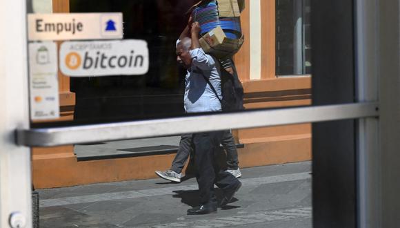 Un hombre camina frente a un letrero de un negocio donde se aceptan pagos en bitcoin en San Salvador, el 17 de noviembre de 2022. (Foto de Marvin RECINOS / AFP)