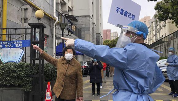 Un trabajador con equipo de protección sostiene un cartel que dice "No amontonar" mientras dirige a un residente cerca de una fila para la primera ronda de pruebas masivas de COVID en el distrito de Jingan en el oeste de Shanghái, China.