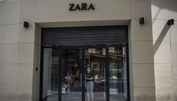 Una trabajadora abre la puerta de una tienda de la cadena minorista de ropa española Zara para que entre su colega, en Sevilla el 7 de mayo de 2020, mientras el país se prepara para aliviar sus duras medidas de bloqueo. (Foto por CRISTINA QUICLER / AFP)