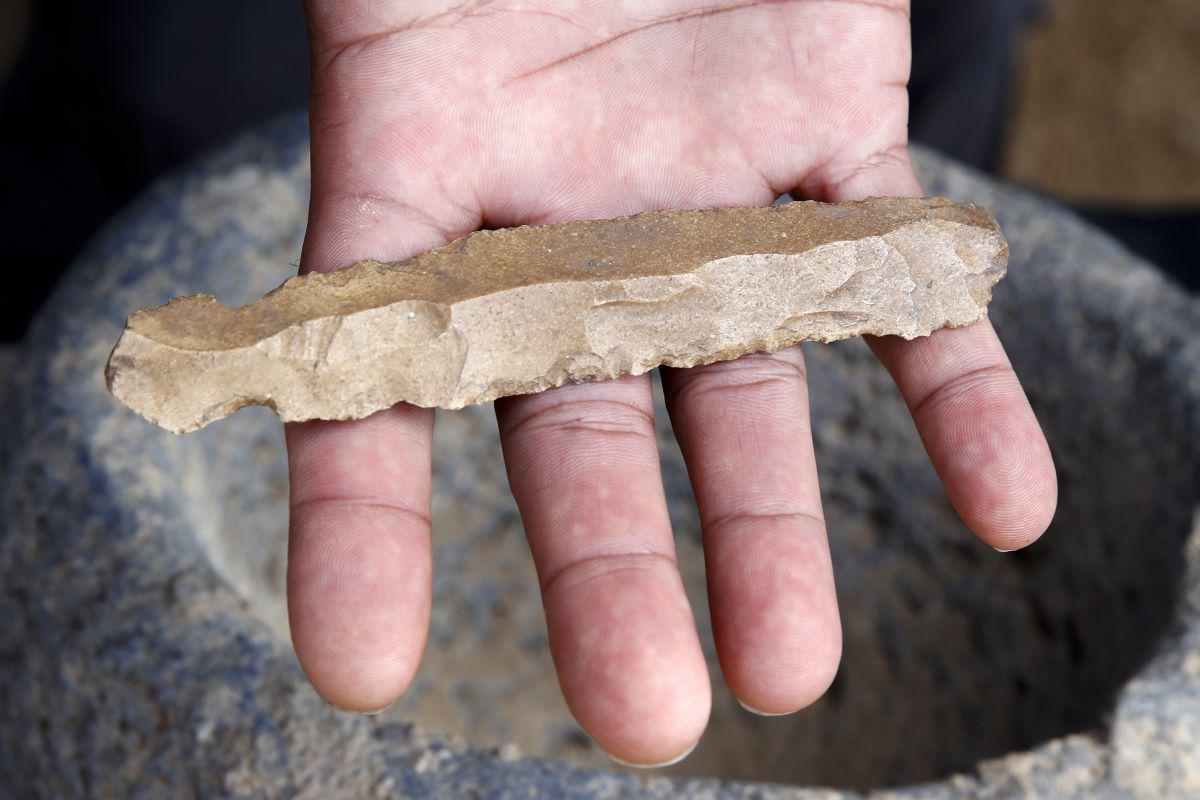 A worker shows a flint knife unearthed at the archaeological site of En Esur (Ein Asawir) where a 5000-year-old city was uncovered, near the Israeli town of Harish, on October 06, 2019. - Archaeologists from the Israel Antiquities Authority said the excavations carried out over the course of two and a half years revealed a city among the biggest from its era in the region, including fortifications, a ritual temple and a cemetery. (Photo by JACK GUEZ / AFP)