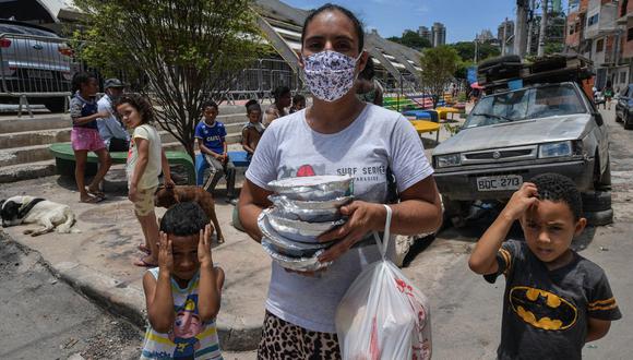 Celia da Costa Gomes, residente de la favela de Paraisopolis, camina a casa con sus hijos después de recibir una comida, en Sao Paulo, Brasil, el 28 de enero de 2021. (Foto de NELSON ALMEIDA / AFP)