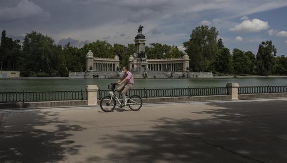 Un hombre con una máscara protectora monta una bicicleta por el parque del Retiro en Madrid, España, el lunes 25 de mayo de 2020. (AP/Bernat Armangue).